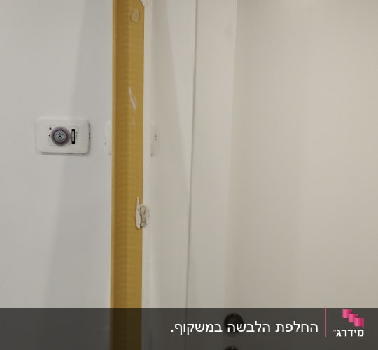 דלת לבנה עם ידית מתכת ומסגרת צהובה